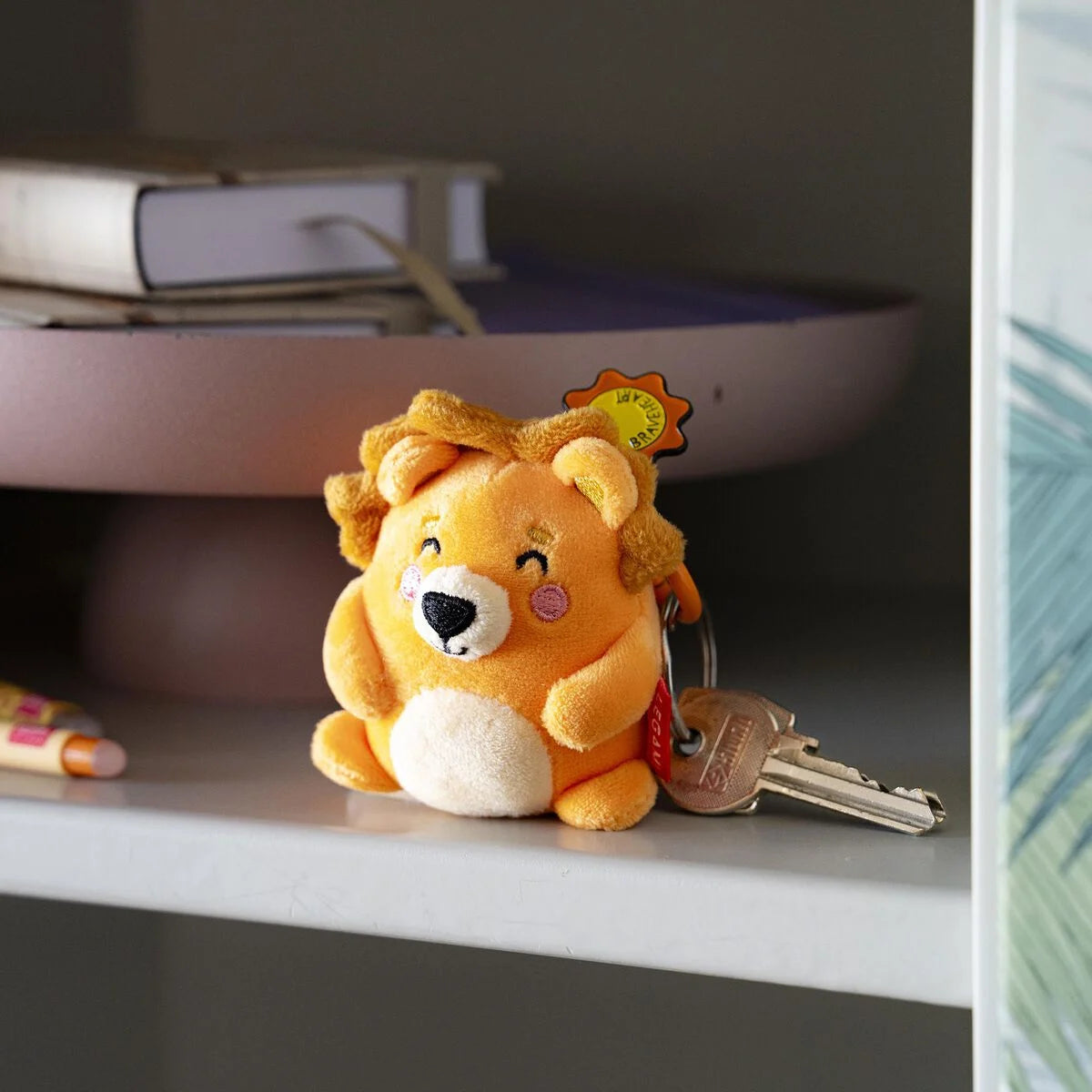Plush lion key ring with a key on a shelf